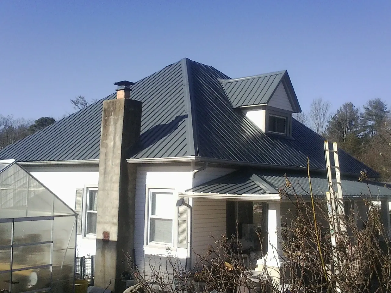 Dark blue standing seam metal roof on a white farmhouse with dormer — Slate & Tile Roof Repair by Roofing Brothers in Darragh