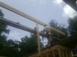 Carpenter setting a ridge beam over a new addition frame — Ice Dam Removal by Roofing Brothers in Darragh
