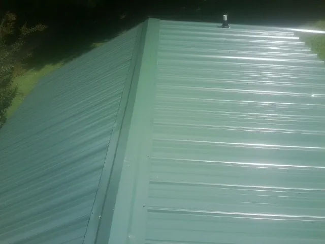 New green metal panels meeting at the ridge of a roof — Flat Roof Repair work by our crew in Darragh