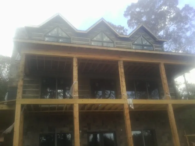 Dormers and porch framing on a large log home under construction — Roof Coating work by our crew in Darragh