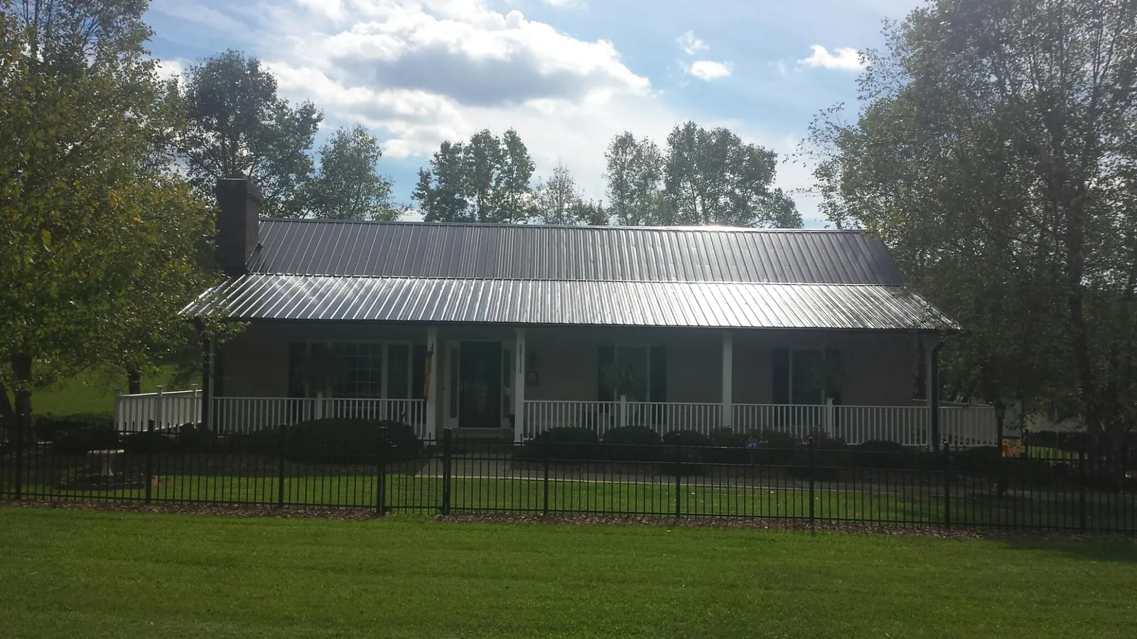 Gray metal roof on a brick ranch with a full width front porch — Gutter Guard Installation work by our crew in Darragh