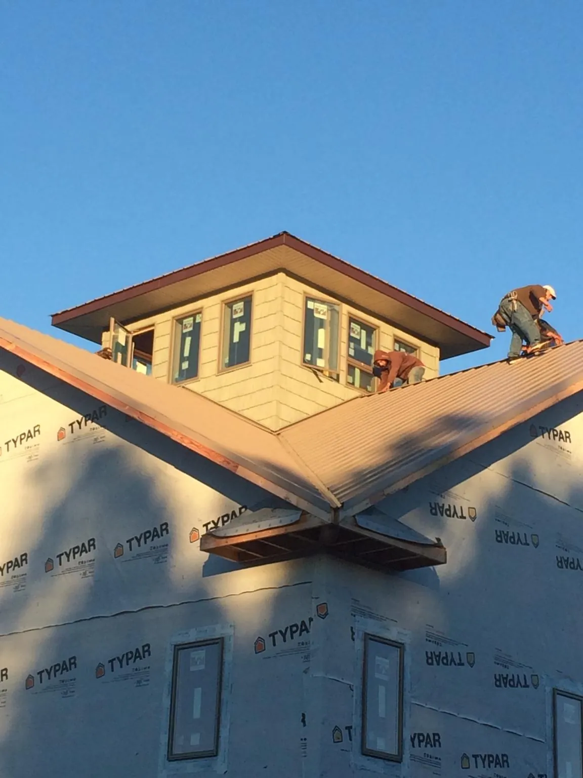 Roofers working around a rooftop cupola on a new metal roof at sunset — Roof Waterproofing in Darragh by Roofing Brothers